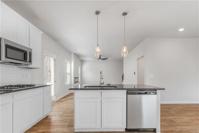 Kitchen with stainless steel appliances, light wood-style flooring, backsplash, white cabinetry, and recessed lighting