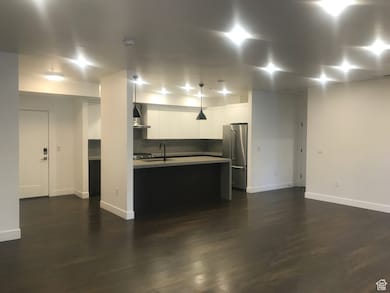 Kitchen featuring refrigerator, dark wood-style floors, white cabinetry, light countertops, and modern cabinets