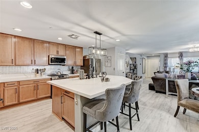 Kitchen with a kitchen breakfast bar, open floor plan, light wood-style floors, hanging light fixtures, and recessed lighting