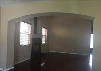 Unfurnished living room featuring healthy amount of natural light, dark wood finished floors, arched walkways, and a glass covered fireplace