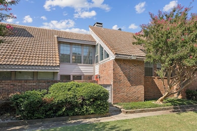 View of side of home with brick siding, a tile roof, and a chimney