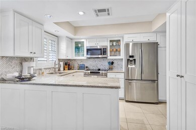 Kitchen featuring stainless steel appliances, light stone countertops, a sink, visible vents, and a peninsula