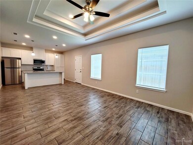 Unfurnished living room featuring dark wood finished floors, a tray ceiling, recessed lighting, and ceiling fan