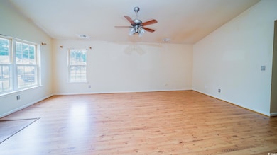 Empty room with light wood-type flooring, ceiling fan, baseboards, and lofted ceiling