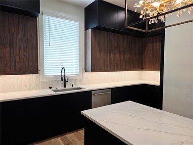 Kitchen featuring a sink, modern cabinets, a chandelier, and light stone countertops