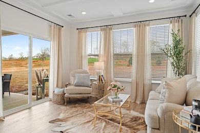 Living area featuring crown molding, healthy amount of natural light, wood finished floors, recessed lighting, and coffered ceiling