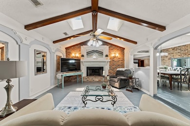 Spacious living room features wood beams, lovely crown moulding and a brick accent wall.