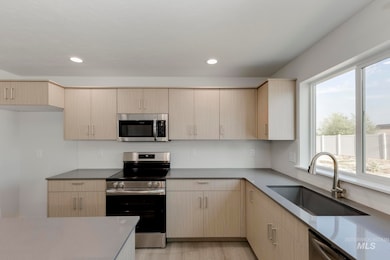 Kitchen featuring appliances with stainless steel finishes, light brown cabinetry, light stone countertops, recessed lighting, and light wood-type flooring