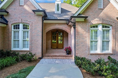 Doorway to property with a shingled roof and brick