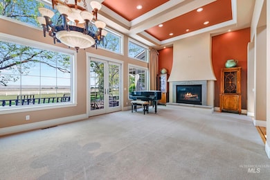 Living area featuring a tray ceiling, french doors, carpet, a glass covered fireplace, and crown molding
