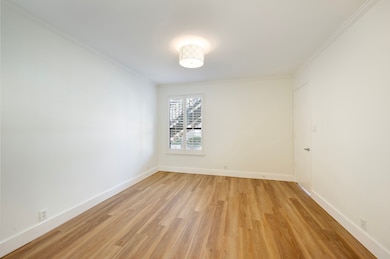 Unwind in the spacious primary bedroom, with new flooring, elegant crown molding, contemporary light fixture, and large window with plantation shutters that creates a peaceful retreat.