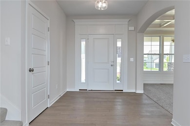 Entrance foyer with arched walkways, wood finished floors, and baseboards