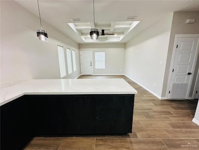 Kitchen with coffered ceiling, a ceiling fan, light wood-style floors, light stone countertops, and open floor plan