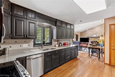 Kitchen featuring sink, dishwasher, backsplash, light wood-type flooring, and lofted ceiling