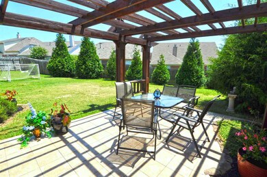 The large patio is covered by a custom arbor for a