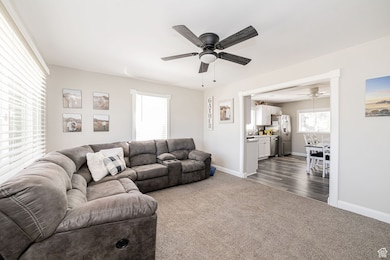 Living area with dark colored carpet and a ceiling fan