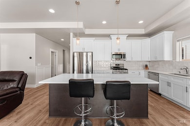 Kitchen with appliances with stainless steel finishes, a kitchen island, light countertops, decorative backsplash, and light wood-style floors