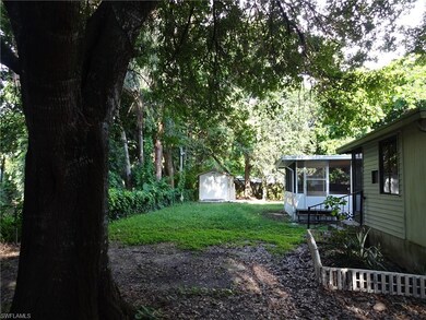 REAR VIEW OF THE HOME, WITH THE SCREENED REAR LANAI OR DECK.    CHAIN LINK FENCE AROUND THE ENTIRE HOME.  PERMITTED SHED IN THE REAR YARD AS WELL.  AMAZING MATURE TREES PROTECTED THIS HOME FROM THE STORM.