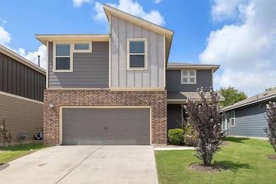 View of front of house featuring board and batten siding, driveway, a front yard, and brick siding