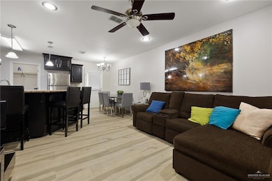 Living area featuring recessed lighting, ceiling fan with notable chandelier, and light wood-type flooring