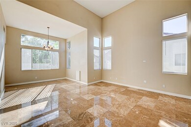 Empty room featuring a chandelier, light marble finish floors, and a towering ceiling
