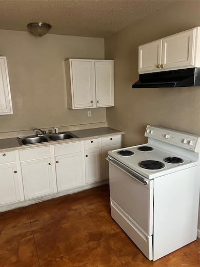 Kitchen with stove, exhaust hood, a sink, white c