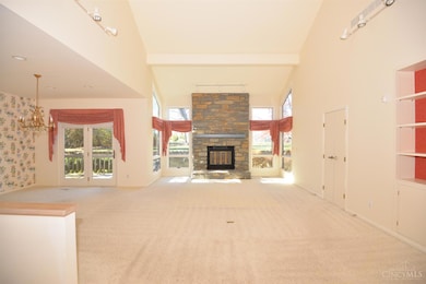 The living room or great room is 24 ft by 15 ft, with a 22-ft ceiling vault to the center of the house. This is the view from the front entry foyer. Each interior wall has a set of trak lighting with three lamps on each trak, totaling 12 lamps. The central fieldstone raised-hearth fireplace has a large mantel... and the firebox shows no fires ever lit. There are built-in bookcases to the front of the room, french doors on the right to access bedroom #2, which could also be used as a study. The great room is open to the dining room to the left, which has a walkout to the rear deck. Oversize windows are on either side of the stone hearthwall and awning style windows open at the bottom of all the windows. the flooring is presently wall-to-wall carpeting.