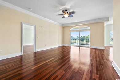 Unfurnished room with dark wood-style floors, a ceiling fan, and crown molding