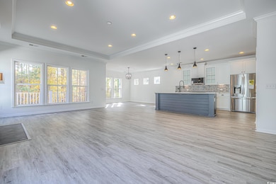 Unfurnished living room featuring sink, a raised c