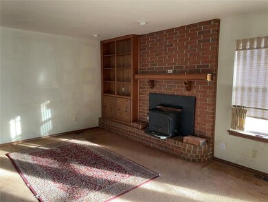 Unfurnished living room with a wood stove, carpet flooring, and built in features