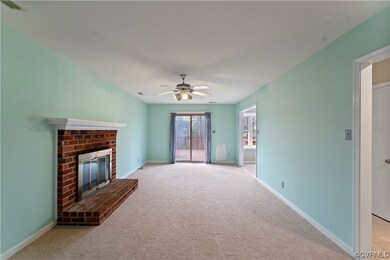 Unfurnished living room with a brick fireplace, ceiling fan, and light carpet