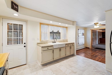 Kitchen with recessed lighting, a baseboard heating unit, stainless steel range oven, a ceiling fan, and ornamental molding