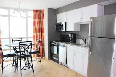 Kitchen with sink, white cabinets, light tile patterned floors, light stone counters, and stainless steel appliances