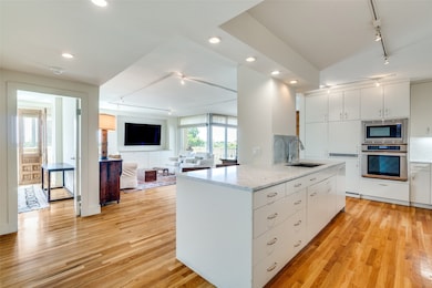 Kitchen featuring track lighting, stainless steel appliances, light wood-style flooring, recessed lighting, and white cabinets