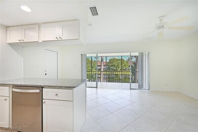 Kitchen featuring stainless steel dishwasher, light stone countertops, light tile patterned flooring, and white cabinets