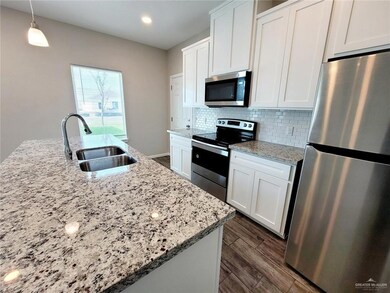 Kitchen with backsplash, a sink, stainless steel appliances, white cabinets, and dark wood-type flooring