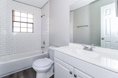 Bathroom featuring vanity, washtub / shower combination, and wood finished floors