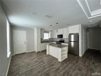 Kitchen featuring stainless steel appliances, a sink, dark wood-type flooring, and white cabinetry