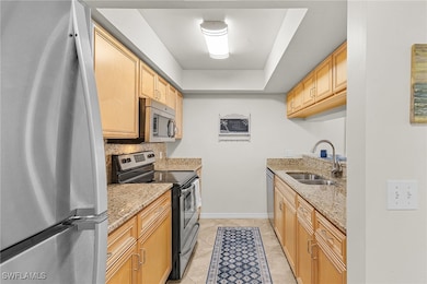 Kitchen with light stone countertops, a sink, ligh