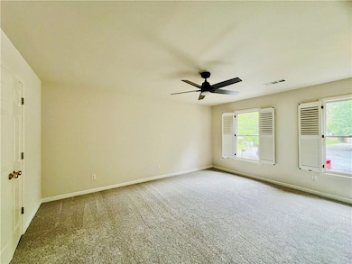 Empty room featuring carpet floors, ceiling fan, and healthy amount of natural light