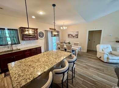 Kitchen with a sink, a chandelier, decorative backsplash, light wood finished floors, and light stone counters