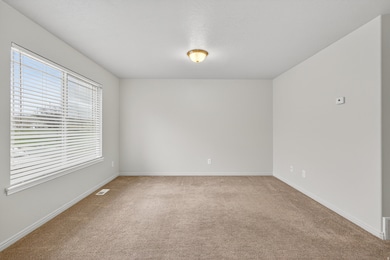 Empty room with light colored carpet and a textured ceiling