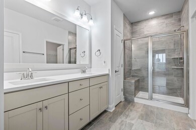 Bathroom with double vanity, a shower stall, a spacious closet, and recessed lighting