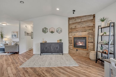 Living area featuring light wood-type flooring, lofted ceiling, a large fireplace, and recessed lighting