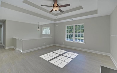 Unfurnished room featuring a tray ceiling, baseboa