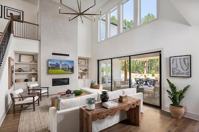Living area with a high ceiling, built in features, baseboards, a chandelier, and hardwood / wood-style floors