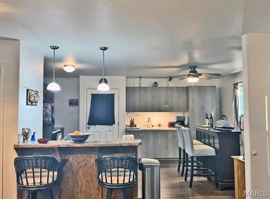 Kitchen with a kitchen breakfast bar, a peninsula, pendant lighting, and dark wood finished floors