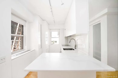 Kitchen with white cabinetry, rail lighting, a peninsula, modern cabinets, and light stone countertops