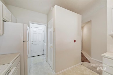 Kitchen featuring freestanding refrigerator, white cabinetry, light countertops, range, and a textured ceiling
