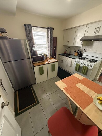 Kitchen with stove, fridge, dark tile patterned floors, extractor fan, and decorative backsplash